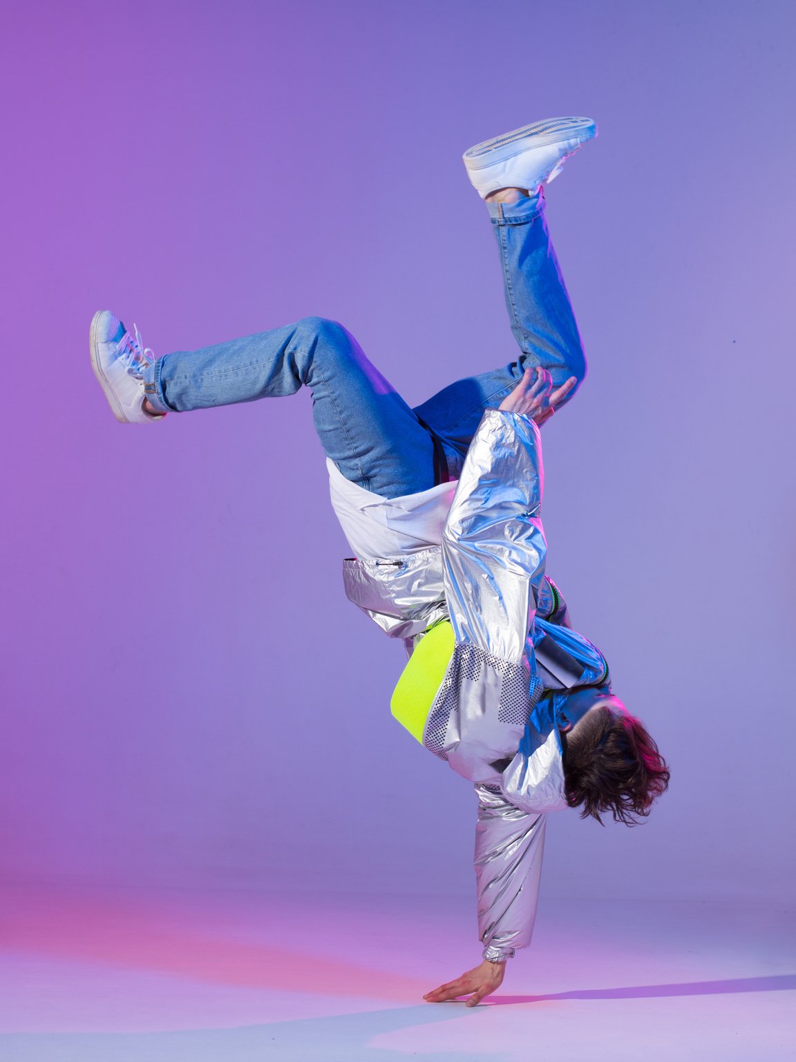 Cool guy dancing contemporary dance in studio. Neon light background. Acrobatic bboy dancer. Break dance lessons.